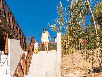 Rear view of men walking on staircase against blue sky