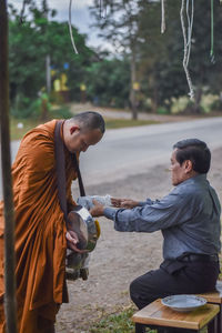 Man giving food to monk