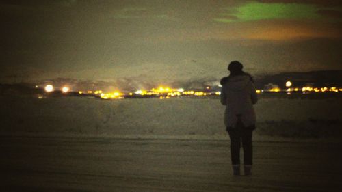Rear view of silhouette man standing on beach at night