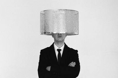 Portrait of man with strange hat standing against white background