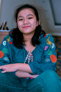 Portrait of smiling young woman sitting at home