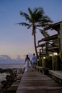 Rear view of couple standing at beach against sky