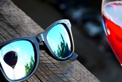 Reflection of wineglass on sunglasses at wooden table
