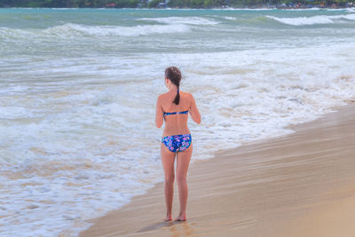 Rear view of woman wearing bikini while standing at beach
