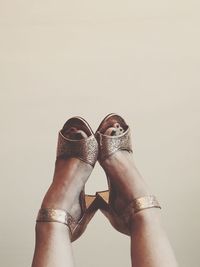 Low section of woman wearing high heels against white background