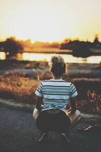 Rear view of woman sitting on beach against clear sky