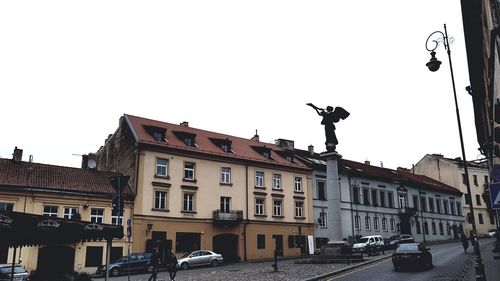 Statue in city against clear sky