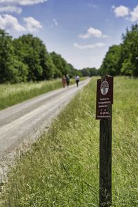 Road sign on field against sky