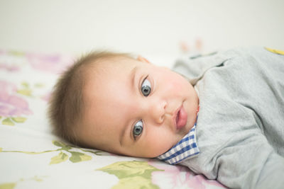 Close-up of cute baby lying on bed