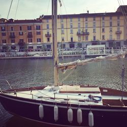 Boats moored on harbor by city against sky