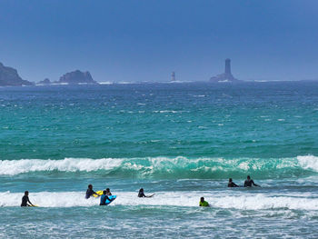 People in sea against sky