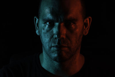 Close-up portrait of serious man against black background