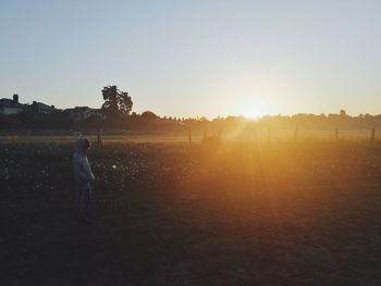 Man standing on field against sky during sunset