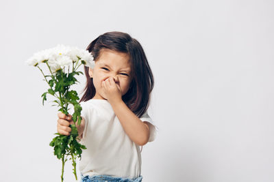 Girl holding bunch of flowers against white background