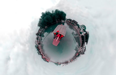 Digital composite image of man standing on globe amidst clouds