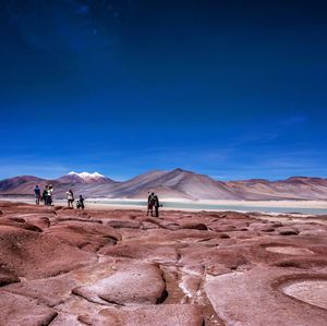 People on desert against mountain range