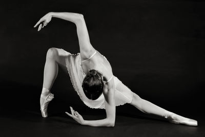 Young woman dancing against black background