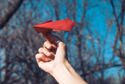 Close-up of person holding leaf against trees