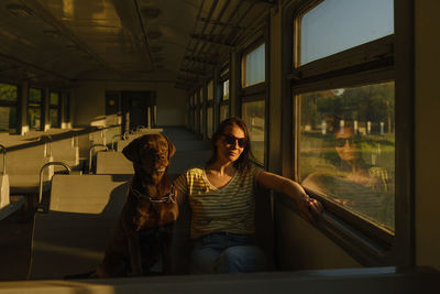 Woman and retriever dog ride a train, look out the window. traveling with a pet on public transport