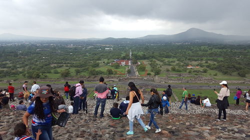 People on mountain against cloudy sky