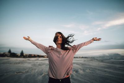 Young woman with arms outstretched standing on beach