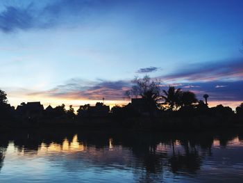 Silhouette trees by lake against sky during sunset