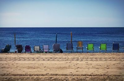 Deck chairs on beach against clear sky