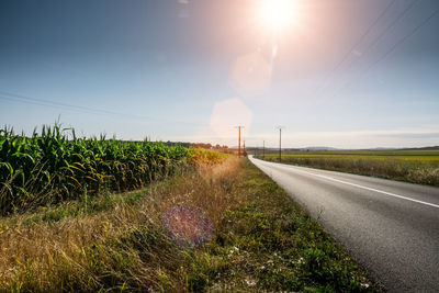 Road amidst field against sky