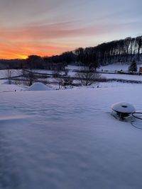 Scenic view of snow covered field against sky during sunset