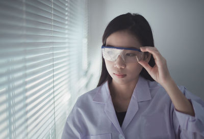 Young woman looking through blinds