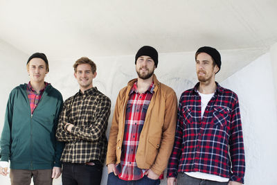 Portrait of young friends standing against wall