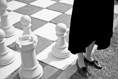 High angle view of woman standing on grass and chess board