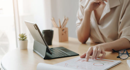 Midsection of woman using laptop on table