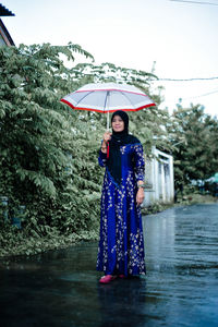 Rear view of woman with umbrella standing in water