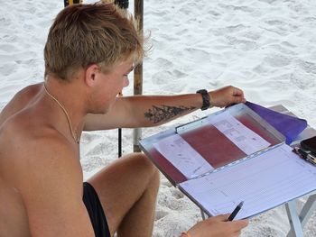 Young millennial man has summer job on sandy beach in tourism.