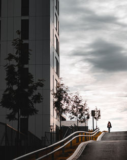 People in modern building against sky in city