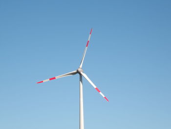 Low angle view of wind turbine against clear blue sky