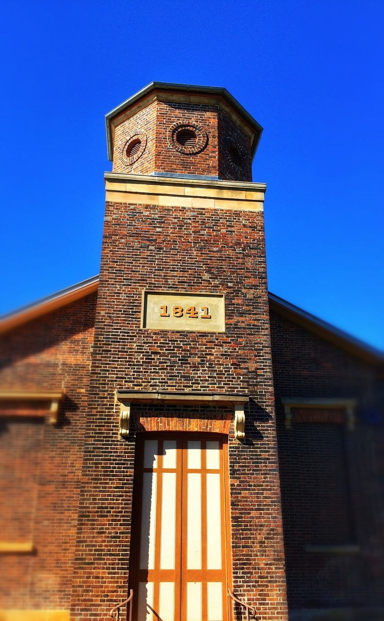 architecture, building exterior, built structure, low angle view, clear sky, blue, religion, church, place of worship, spirituality, clock tower, tower, window, facade, history, day, outdoors, sunlight