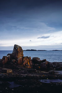 Rock formation on sea shore against sky