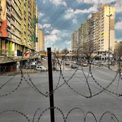 Road by buildings against sky
