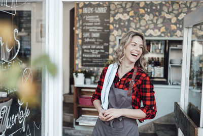 Portrait of smiling young woman standing against wall