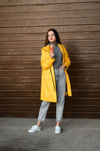 Portrait of young woman standing against wall