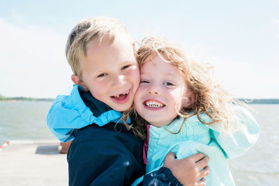 Portrait of brother and sister laughing and hugging at the beach