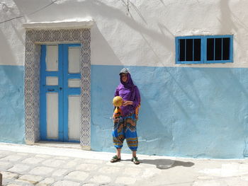 Full length of girl holding ball while standing against building