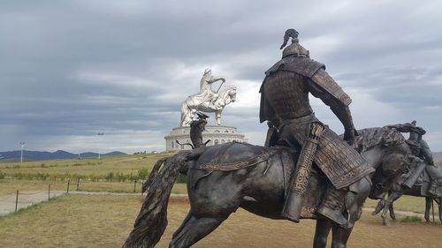 Statue of a horse on field against sky