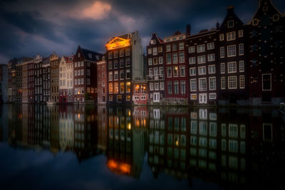 Reflection of buildings on lake against sky in city