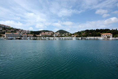 Scenic view of harbor at sea by buildings against sky