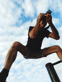 Low angle view of man photographing against sky