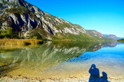 Rear view of man looking at lake against mountain range