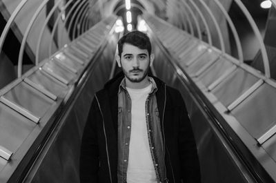 Portrait of young man standing on escalator